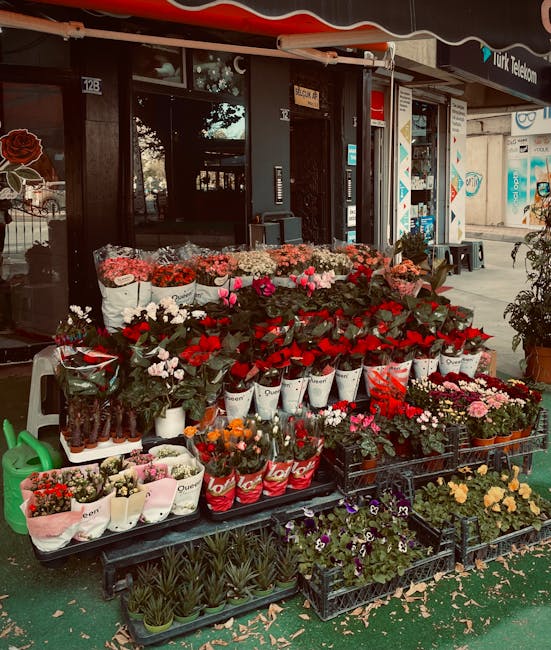 An outdoor display of fresh flowers arranged on black metal and plastic racks in front of a florist shop on Wanstead High Street. The arrangement includes various flower types such as red roses, pink